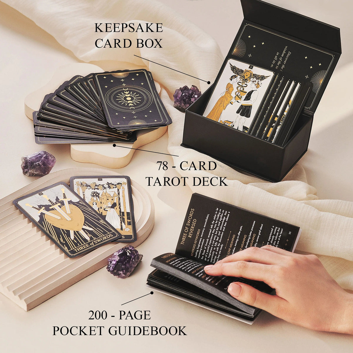 Set of tarot cards with a black keepsake card box, 200-page pocket guidebook, and amethyst stones on a light background.