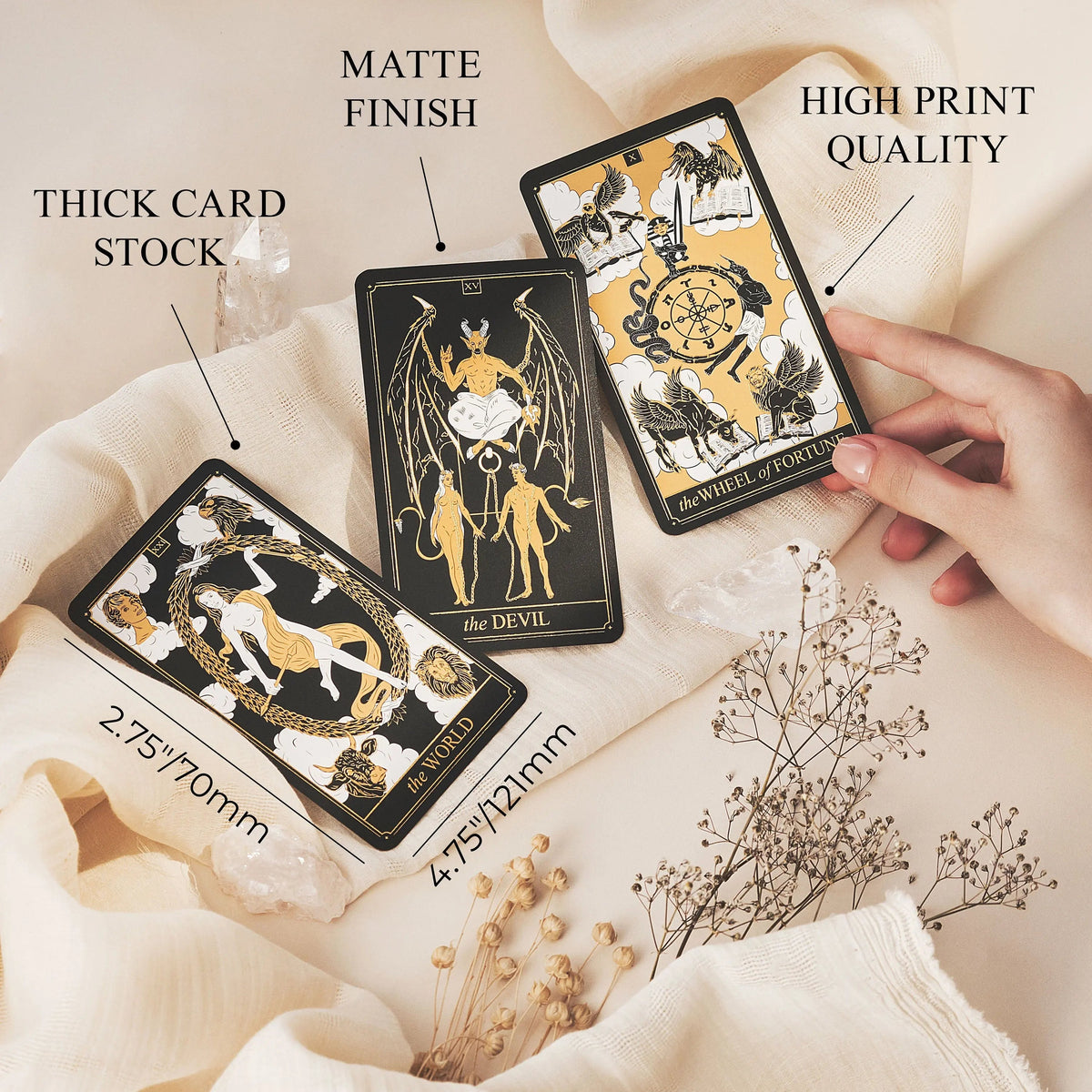 Three tarot cards with text highlighting features like matte finish, thick card stock, and high print quality on a soft fabric background.